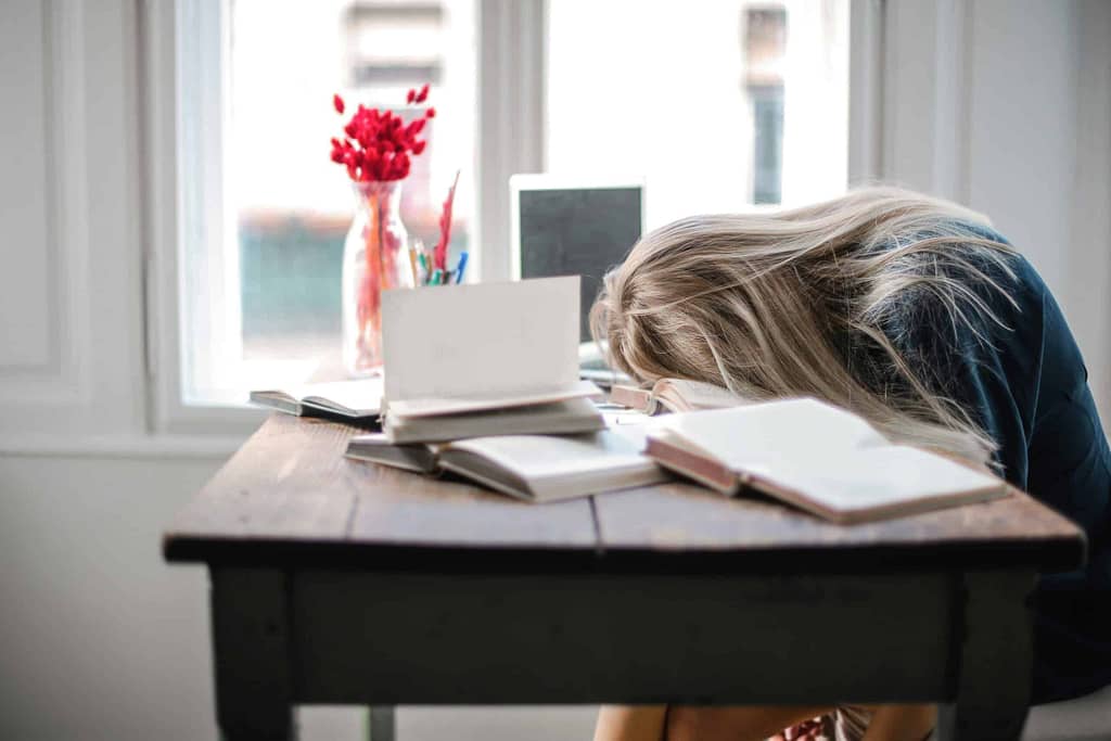 a woman sleeping on a desk with books